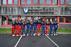 Russen på Nordahl Grieg og Sandsli som står foran logoen til Sandsli vgs utenfor skolen på en rekke