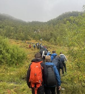Gruppe med elever som går på tur i en skog, på rekke.